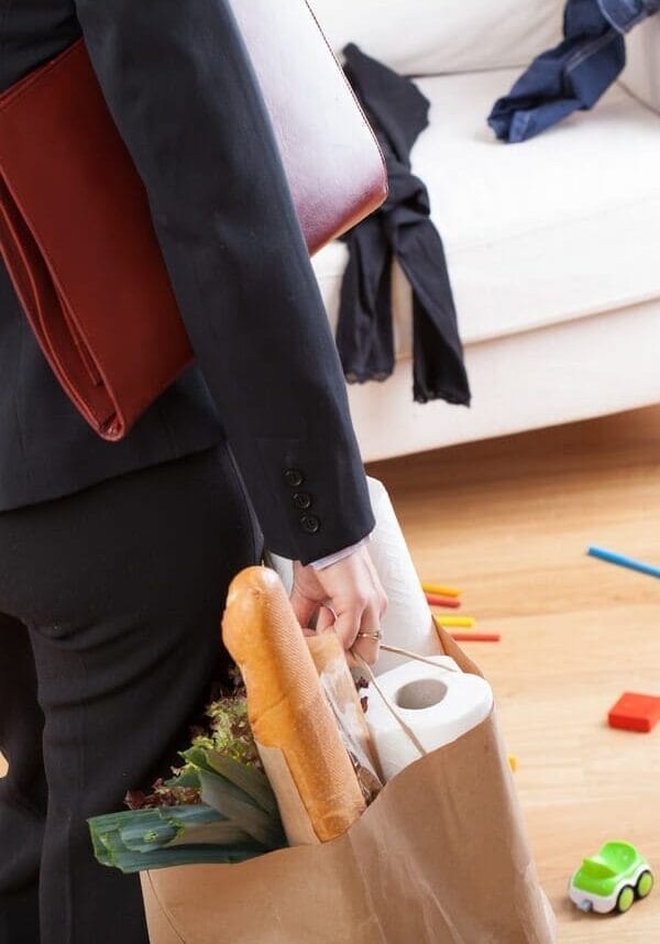 Depositphotos_38446027 A business woman with groceries entering a messy living room